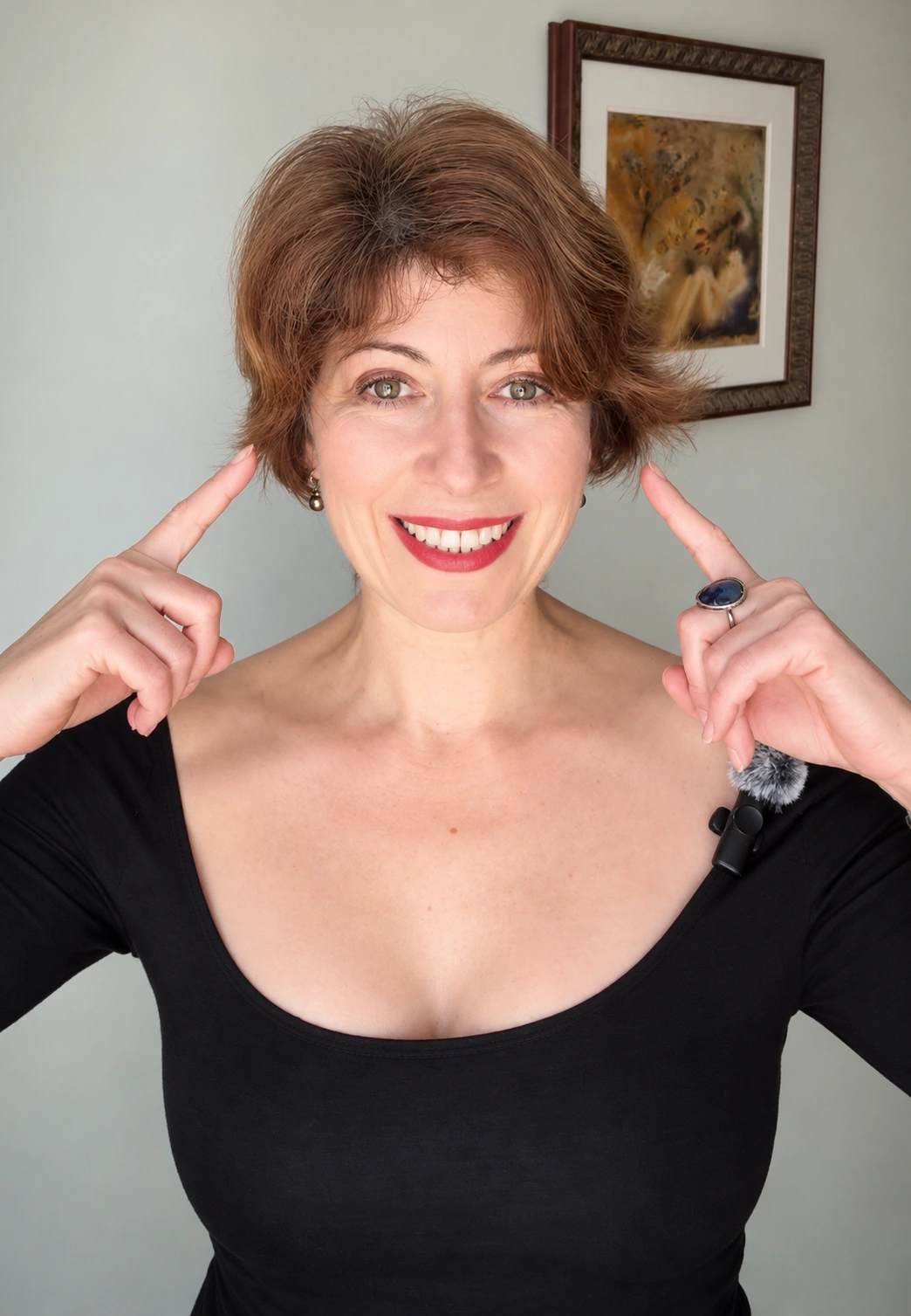 Lana demonstrating face yoga with her fingertips beside her temples.